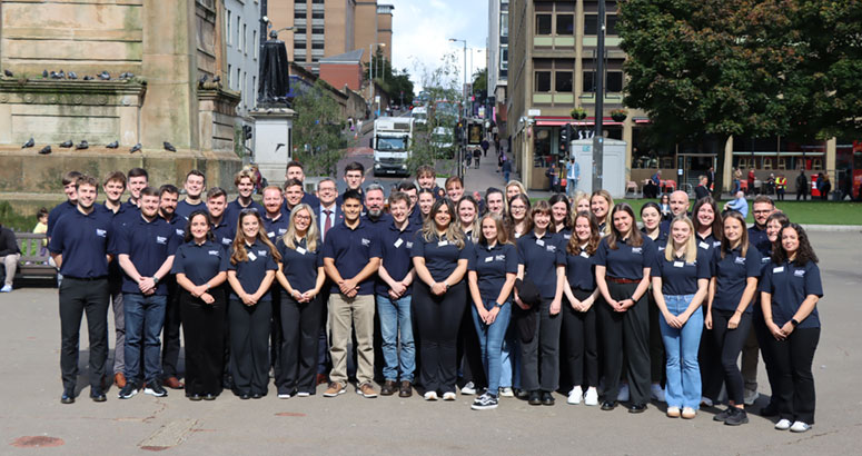 Large group of young men and women standing in the street with buildings in the background