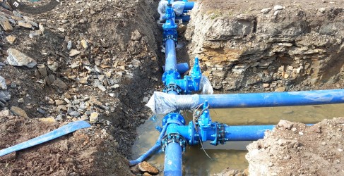 Image of bright blue water main being installed in the ground Image of bright blue water main being installed in the ground