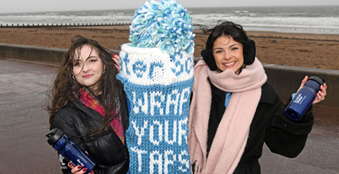 2 women standing with water bottles at a top up tap