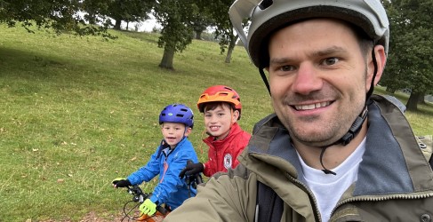 Paul Davidson smiles with two sons, Thomas and Murray Three smiling people posing with cycling clothing on