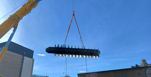 The screw pump is transferred by crane to the installation site The screw pump is shown in the air as it is being transferred to site